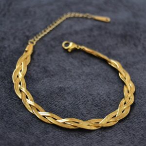 Close-up shot of a luxurious braided gold necklace on a textured dark background.