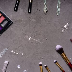 Stylish makeup arrangement featuring a diverse palette and brushes against a gray background.